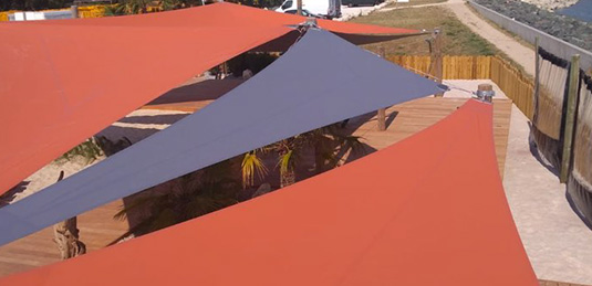 Voiles d'ombrage oranges et grises sur terrasse de restaurant