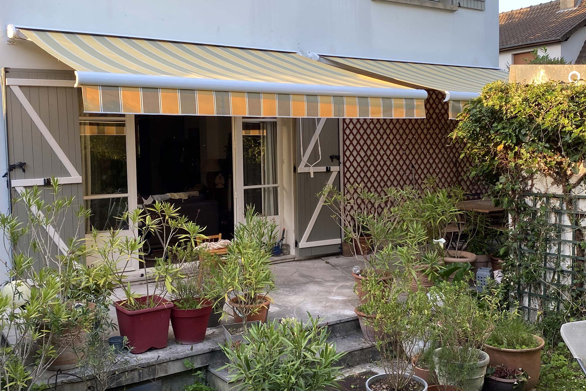 Store Banne Coffre Cereza avec toile de store banne rayée et lambrequin sur une terrasse